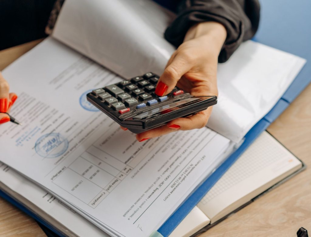 Person using calculator and documents for accounting tasks in an office setting.